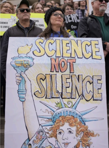 ACTIVIST WEARS a sign at a Stand up for Science rally